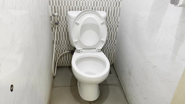 Clean white ceramic toilet with vertical stripe tiled wall