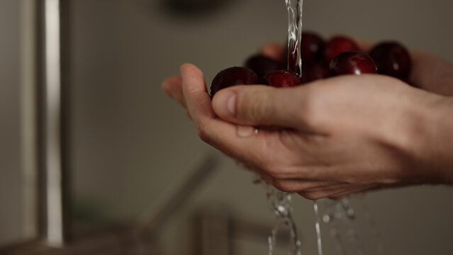 closeup shot of man washing cherries with kitchen faucet