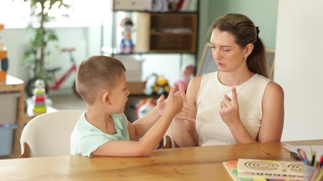 Boy makes movements with his fingers, repeats after teacher and performs tasks for fine motor skills. Training of attention, perseverance, attentiveness for children with special needs