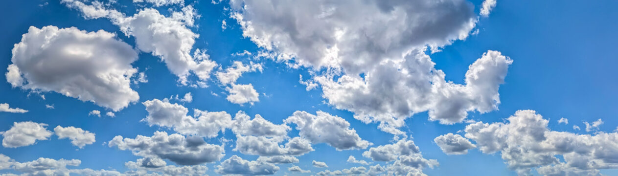 A few cumulus clouds obscure the sky, creating a window of blue sky. A bright summer sky in fine weather. Detailed wide panorama cloud ways from wind.
