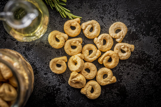 Golden Taralli Italian Snack Rings With Olive Oil and Rosemary On Dark Background