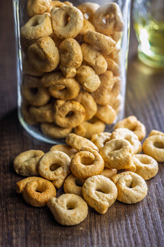 Close-Up of Italian Taralli Cookies Piled on Wooden Table With Glass Jar in Background