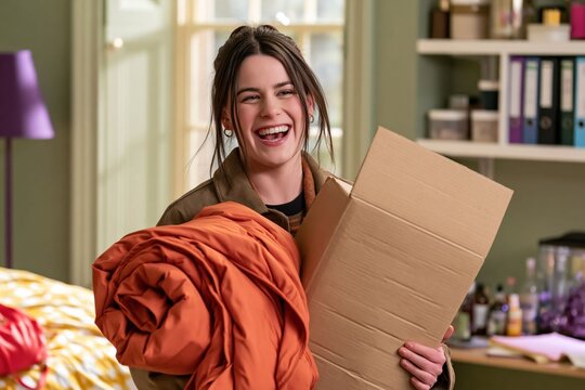 Young woman packs her belongings into a cardboard box while moving out of a dorm room, relocation and a fresh new beginning.