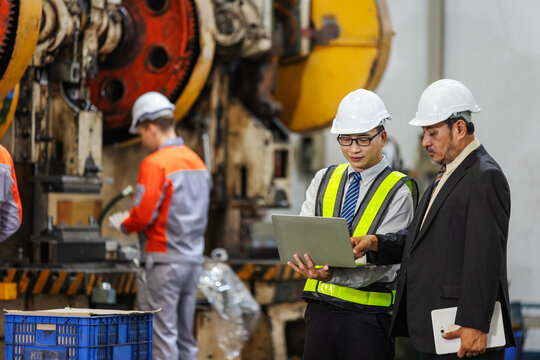 Factory Engineer Presenting Manufacturing Performance Report to Executive Using Laptop in Industrial Plant