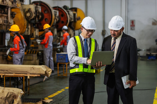 Factory Engineer Presenting Production Data to Business Executive Using Laptop in Manufacturing Plant