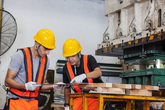 Industrial Engineers Inspecting Metal Panel Before Production on Heavy Press Machine
Description