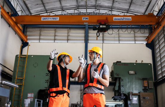 Industrial Engineers Inspecting Overhead Crane Operation for Safe Lifting in Manufacturing Factory