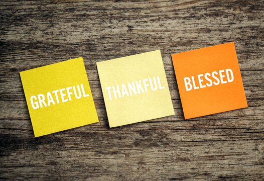 Colorful sticky notes with grateful thankful and blessed words on wooden background for inspiration and positivity