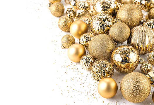 Festive collection of shiny gold and glittery christmas ornaments scattered with confetti sparkles