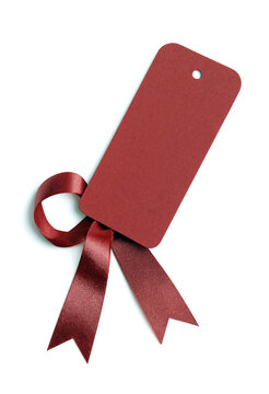 Red gift tag with shiny satin ribbon bow attached isolated for packaging and present wrapping needs