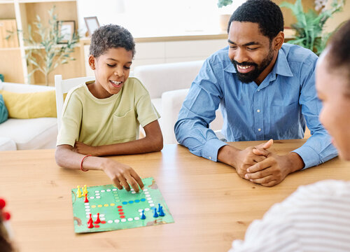 Portrait of a happy african american family at home, having fun playing a board game challenge game, playing board game ludo at home