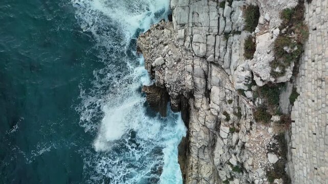 BEAULIEU-SUR-MER, FRENCH RIVIERA, FRANCE - NOVEMBER 2, 2025: Aerial view of waves crashing against a rocky coastline