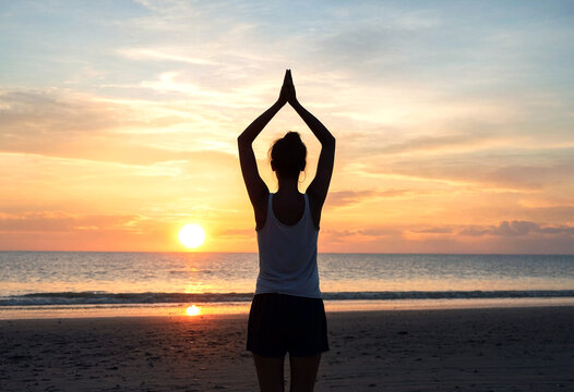 Silhouette of a person meditating on the beach during a beautiful sunset over the ocean waves