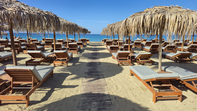 Relaxing beach scene in Agios Arsenios, Naxos, Greece with sun loungers and straw umbrellas