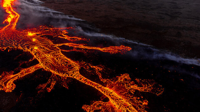 Aerial view of the Litli-Hrutur volcanic eruption with glowing lava flows spreading across the dark volcanic landscape, Grindavik, Grindavikurbaer, Iceland.