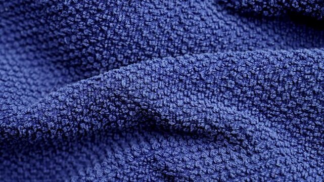 Dark blue terrycloth towel texture with soft folded cotton fabric loops. Fluffy absorbent woven material surface