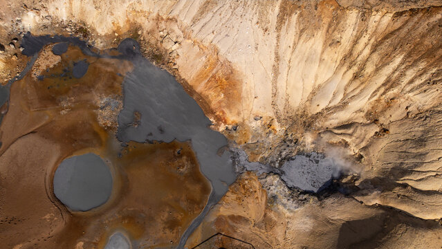 Aerial view of geothermal mud pools and steaming volcanic terrain in Iceland.