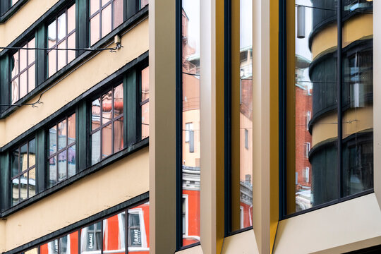 Across a cropped field of glass, a reflection shifts through windows in Oslo, Norway, as abstract facades and vertical frames reshape urban architecture.