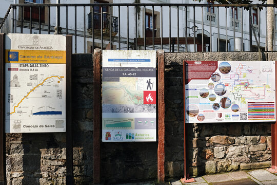 Salas, Asturias, Spain - May 16, 2025: Official Camino de Santiago information boards for the Salas to Tineo hiking stage and local trails on a stone wall.