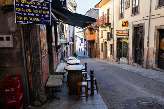Tineo, Asturias, Spain - May 16, 2025: Traditional narrow street with an outdoor cafe terrace and a tobacco shop on the Camino Primitivo.