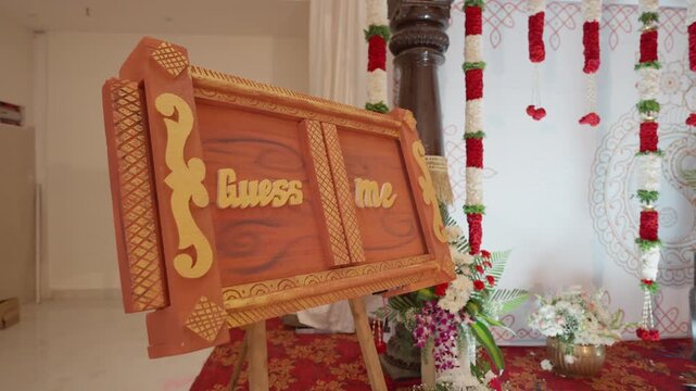 Guess me baby name ceremony board displayed on floral bouquet decorated stage event venue