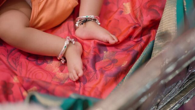Closeup on Indian baby girl feet wearing ornate luxurious ankle bracelet sleeping in her crib