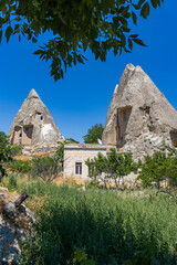 serene rock formations with built-in structures in a rural landscape, ground-level perspective, blue sky and green foliage, stone and concrete materials, architectural and travel themes. © Анастасия Бабак