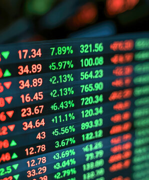 angled view of an electronic stock market ticker display screen. interface features rows of glowing digital data against a dark background, organized into distinct columns