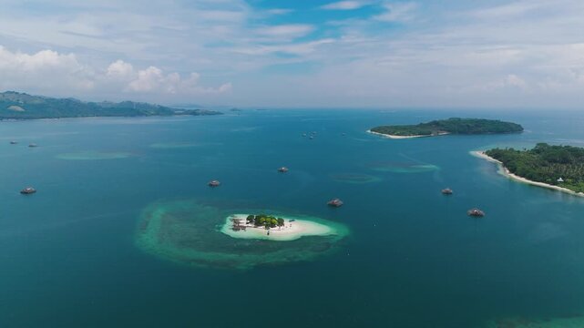 Gili Kedis, Lombok, Indonesia, showing a tiny tropical island surrounded by crystal-clear turquoise water, coral reefs and neighbouring islands, aerial view
