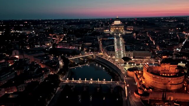 Castel Sant'Angelo, the Tiber River bridges and the lit axis to the Vatican dome glow at dusk in a high aerial flyover.