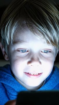 Child Focused on Smartphone Screen in Close Up - A close-up shot of a young Caucasian boy engrossed in content on his smartphone.