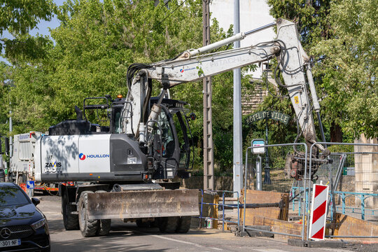 Nancy, France - July 22nd 2026 : View of a 14-tonne grey compact wheeled excavator Hitachi ZX140W-6 on a construction site for work on the drinking water network.