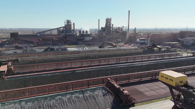 Aerial composition of harbor crane and long structured rows of stored industrial raw material