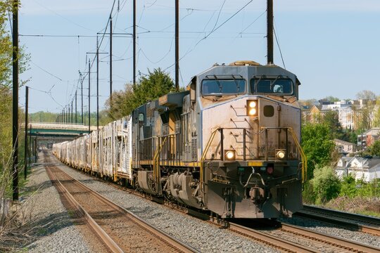 Southbound freight locomotive leading auto transport cars through a Maryland suburb on a spring afternoon