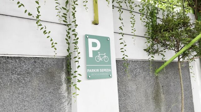 Bicycle parking sign on white wall with green ivy leaves