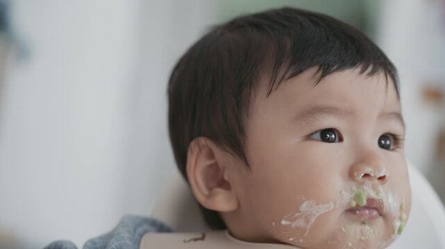 Asian baby boy self feeding sweet corn using baby led weaning method at home.