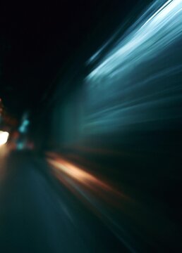 Close-up of a car's headlights at night. the car appears to be moving at a high speed, as the headlights are blurred and creating a sense of movement.