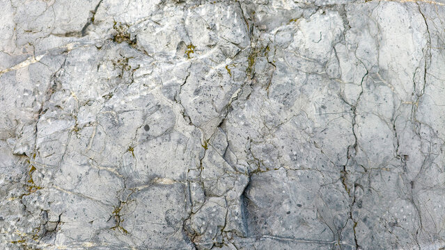 Gray rock texture showing natural cracks, rugged stone surface, and rough granite pattern, displaying aged mineral structure as a weathered background