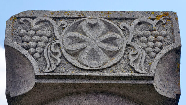 Zvartnots cathedral detail showing ancient armenian stone carvings of a cross symbol and grape clusters, representing christian symbolism and traditional viticulture