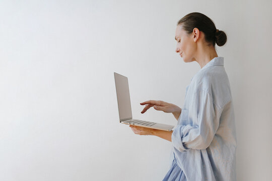 Casual Freelancer Woman In Oversized Blue Button Down Shirt Typing On Portable Laptop