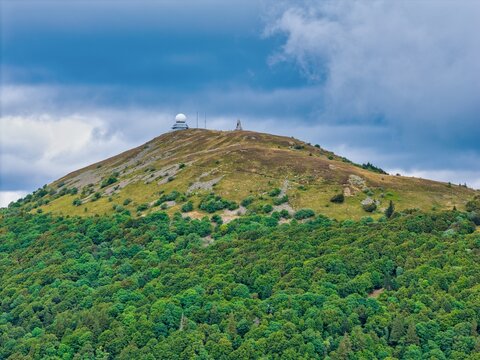 Aerial view of the Grand-Ballon mountain peak with a radar dome and communications tower rising above lush green forests and grassy slopes in Soultz-Haut-Rhin, Grand Est, France.