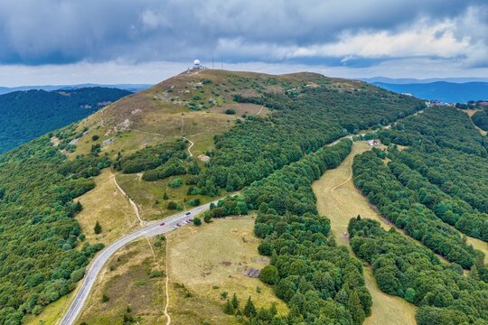 Aerial view of Grand-Ballon mountain with its radar dome, lush green forests, and winding roads in Soultz-Haut-Rhin, Grand Est, France.