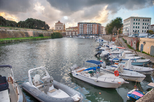 Boats moored in the canals of Livorno, Italy under clouds