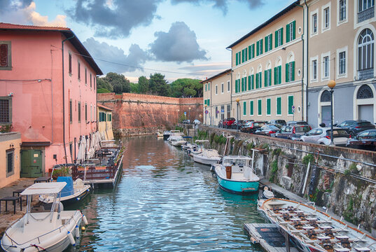 Boats moored in the canals of Livorno, Italy under clouds