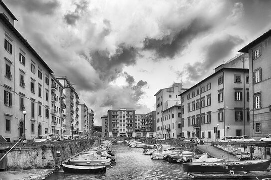 Boats moored in the canals of Livorno, Italy under clouds