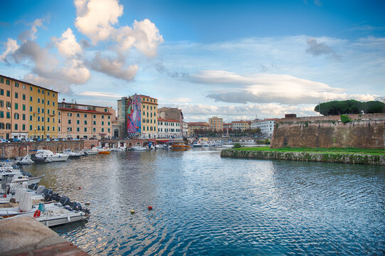 Boats moored in the canals of Livorno, Italy under clouds
