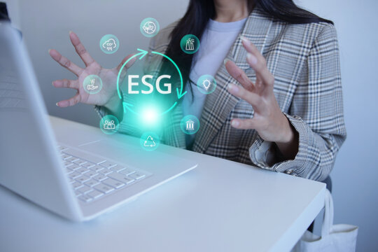Female Hand Gesture Around ESG Hologram Circle Over Laptop Desk