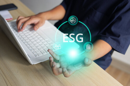 Worker Typing on Laptop While Holding ESG Hologram Above Open Hand
