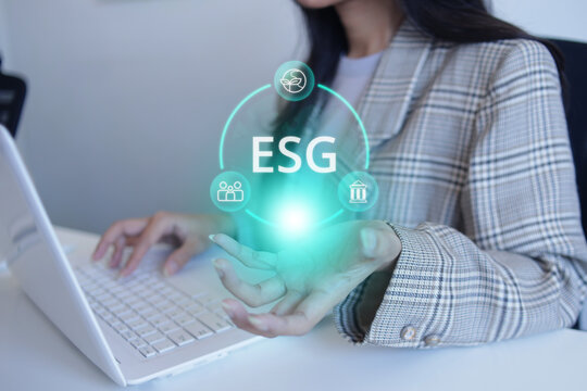 Businesswoman Typing on Laptop While Displaying ESG Circular Hologram Network over Palm