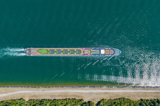 Aerial view of a river cruise ship featuring a putting green and deck furniture sailing on the Rhine river in Kembs, Grand Est, France.